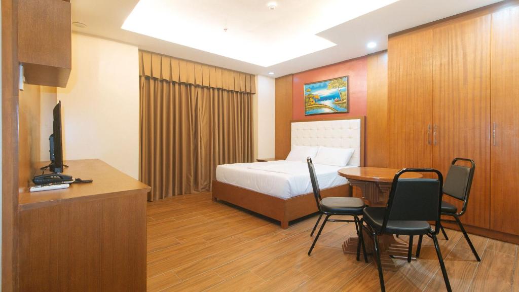 une chambre d'hôtel avec un lit, une table et des chaises dans l'établissement M28 Hotel and Apartments Quezon City, à Manille