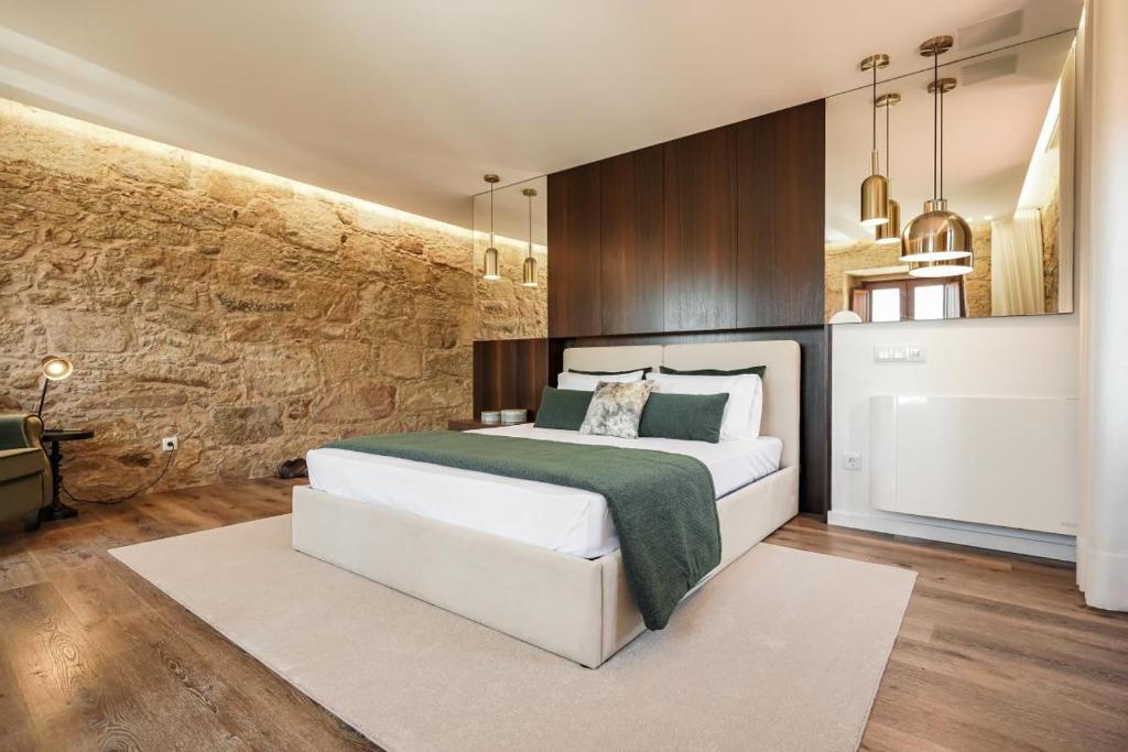 een slaapkamer met een groot wit bed en een stenen muur bij RB Ganfei House in Valença