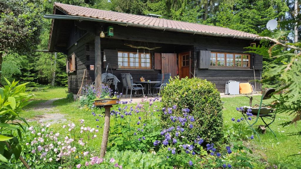 eine kleine Holzhütte mit Blumen davor in der Unterkunft Blockhaus Paepke Dold in Mühlenbach