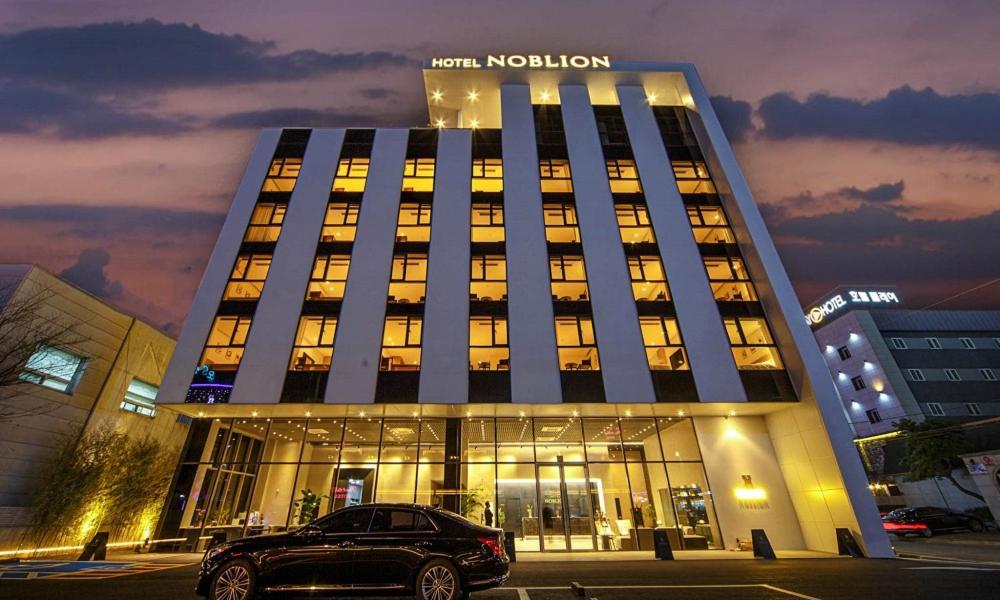 浦项Pohang Hotel Noblion的停在建筑物前的汽车