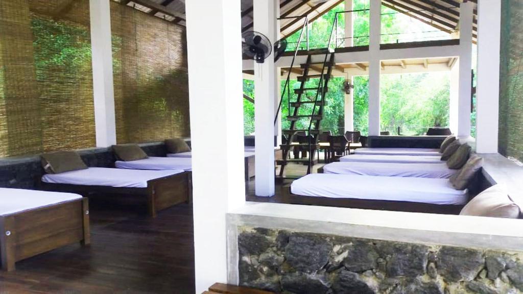 a row of beds in a room with a stone wall at Forest Edge Bungalow - Wilpattu in Radagama