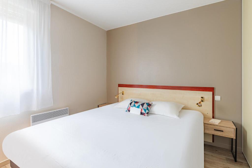 - une chambre avec un lit blanc et une fenêtre dans l'établissement Appart'City Classic Limoges, à Limoges