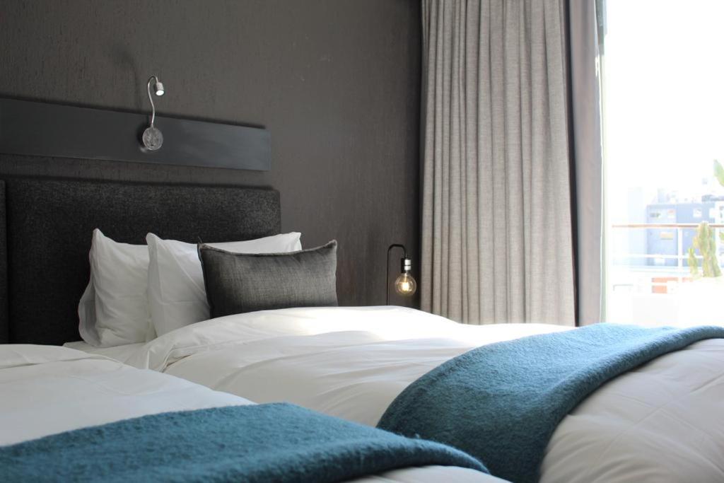 a bedroom with two white beds and a window at Atlantic Affair Boutique Hotel in Cape Town