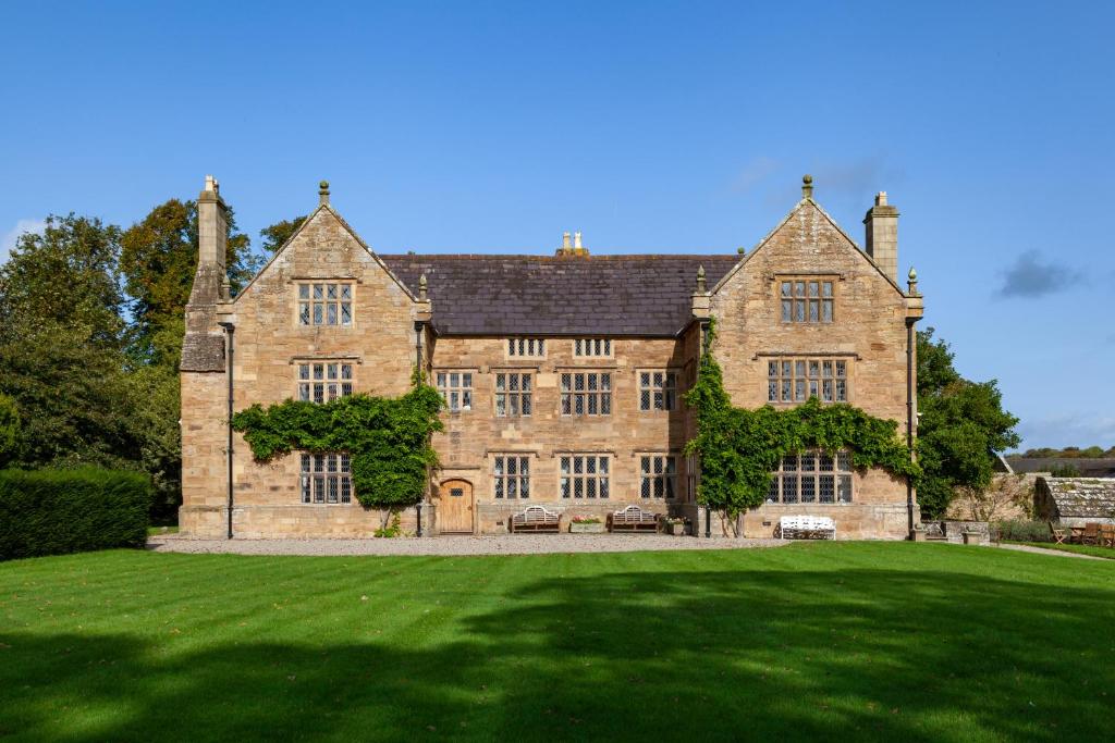 uma grande casa de tijolos com um grande campo de relva em Pentrehobyn Hall em Wrexham