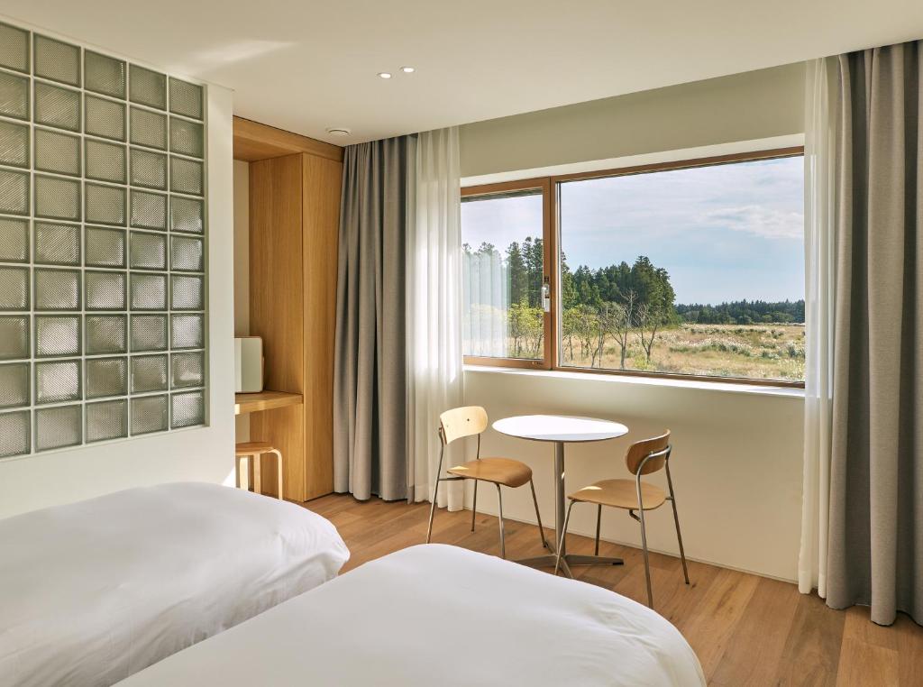 a hotel room with a bed and a table and a window at Gonggan7 in Jeju