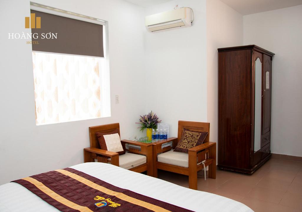 una camera con un letto e due sedie e una scrivania di Hoàng Sơn Hotel ad Ho Chi Minh
