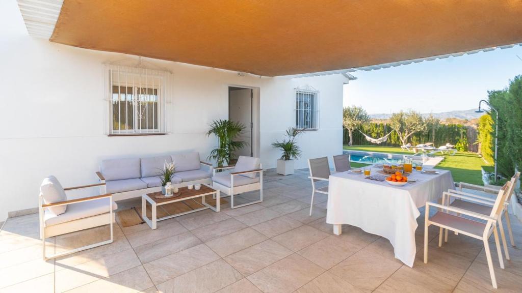 patio ze stołem i krzesłami oraz basenem w obiekcie Casa El Refugio de Paco Alhaurín de la Torre by Ruralidays w mieście Alhaurín de la Torre