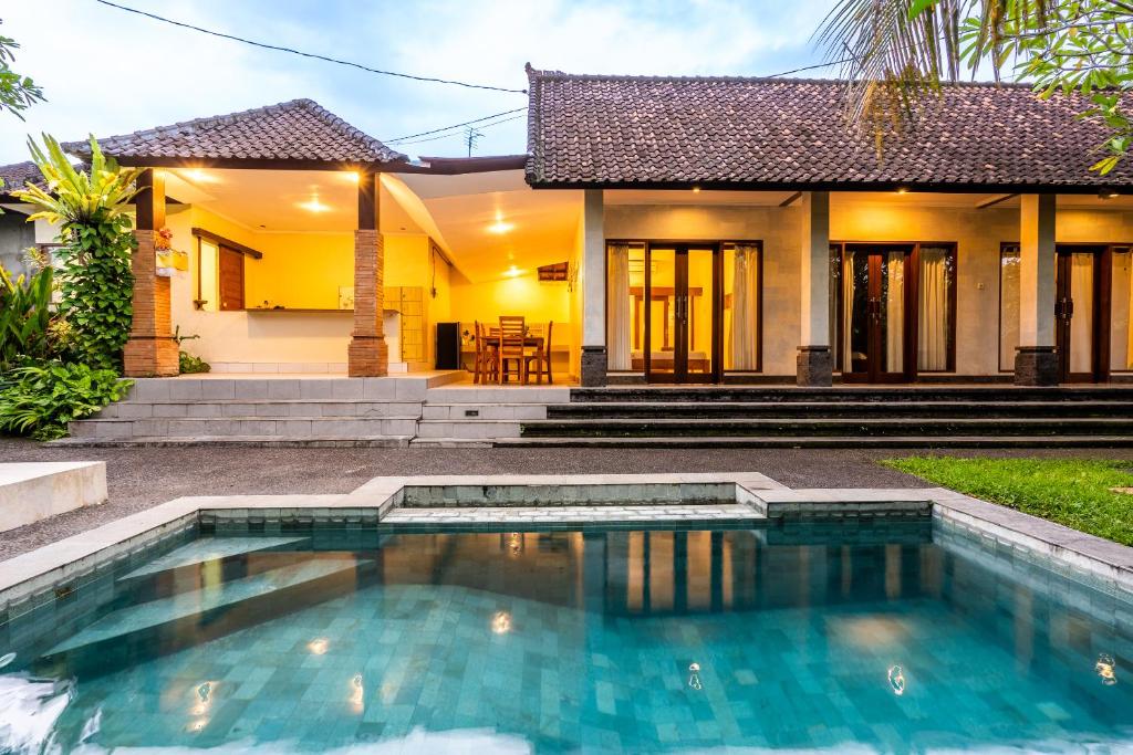 a villa with a swimming pool in front of a house at Uda Suite Guest House 2 in Ubud