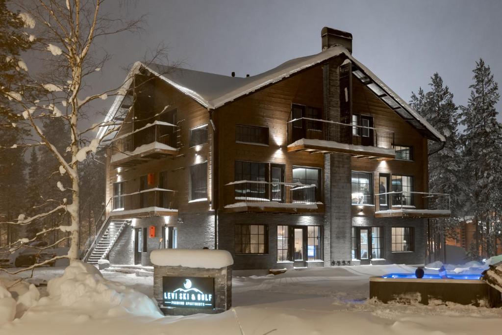 duży budynek w śniegu z pokrytymi śniegiem drzewami w obiekcie Levi Ski & Golf Premium Apartments w mieście Levi