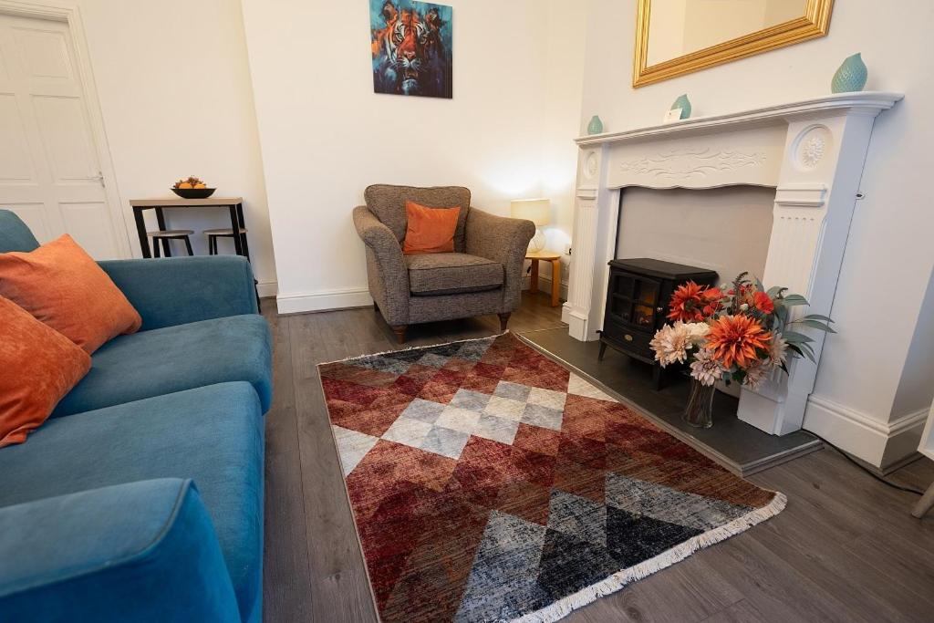 uma sala de estar com um sofá azul, uma cadeira e uma lareira em Suggitt House em Hartlepool