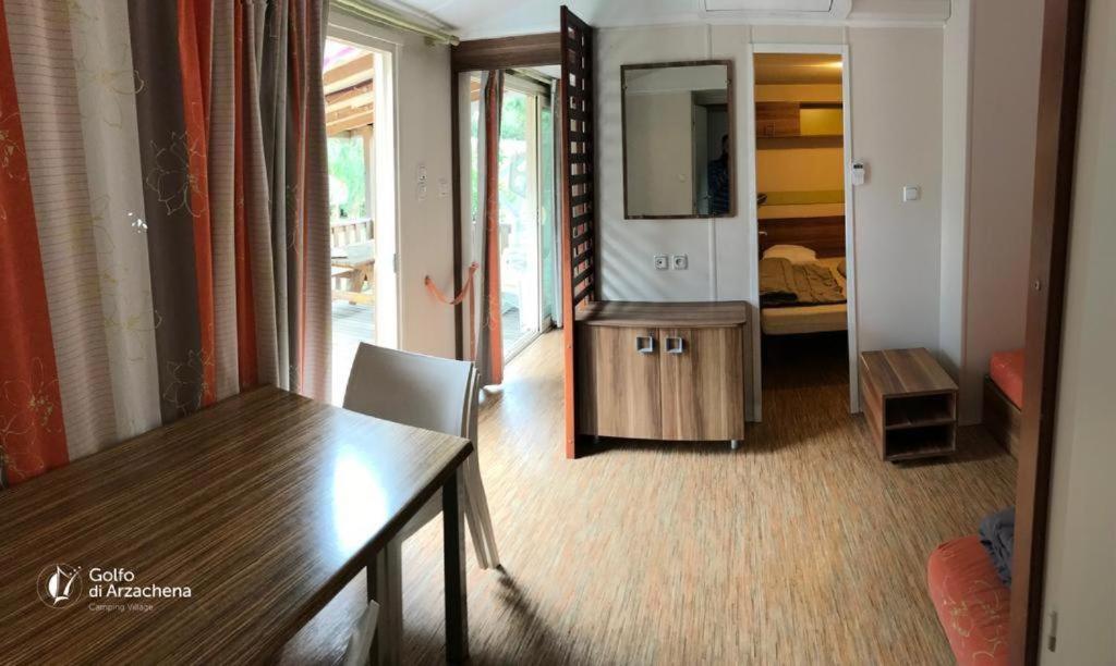 een woonkamer met een tafel en een spiegel bij Villaggio Camping Golfo di Arzachena in Cannigione