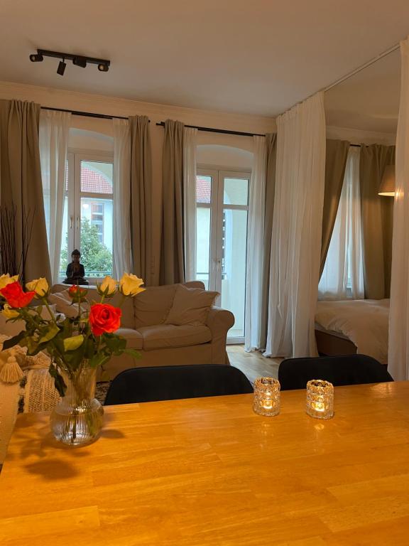 uma sala de estar com um sofá e uma mesa com flores em AnnApartment em Berlim