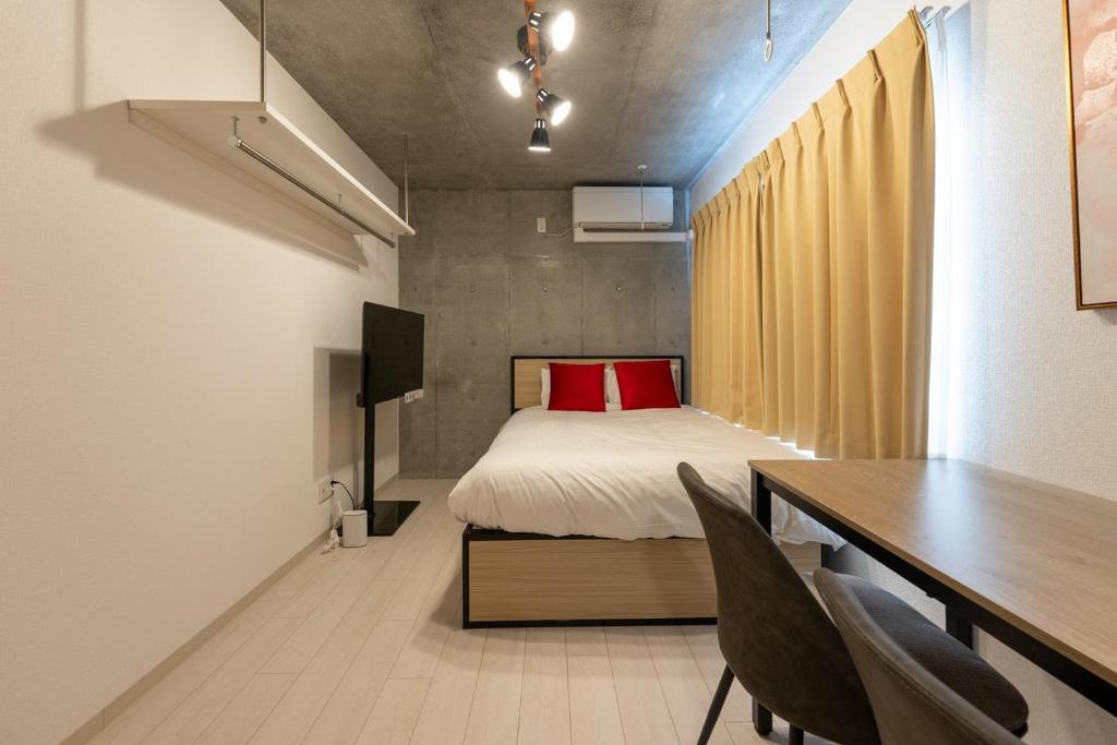 a bedroom with a bed and a desk with chairs at Ferio Kamata in Tokyo