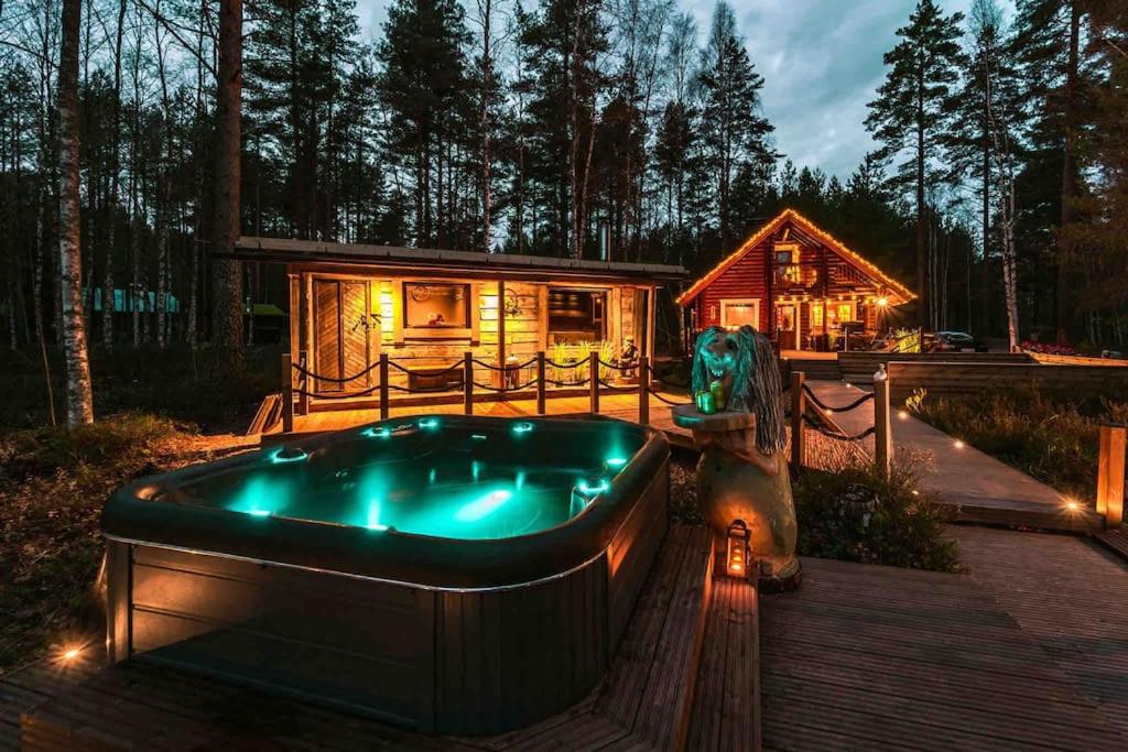 a house with a hot tub in front of a cabin at Minivilla Peikonpesä ulkoporeallas & pihasauna in Loppi