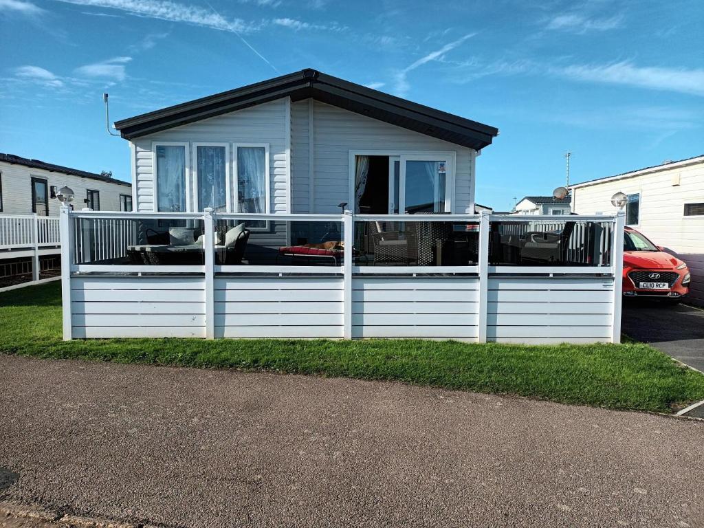 a house with a white fence in front of it at Beautiful 4 Berth Lodge With Free Wifi At Pakefield Holiday Park Ref 68019cr in Lowestoft
