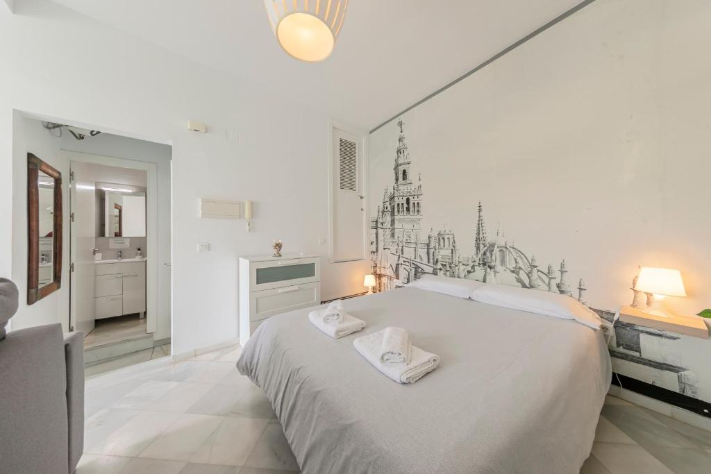 a white bedroom with a large bed with towels on it at Arco del Postigo in Seville