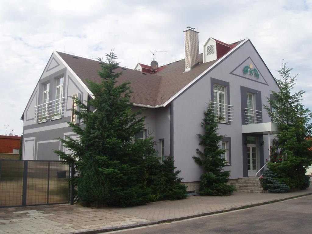 a white house with trees in front of it at Penzion Axa in Hradec Králové