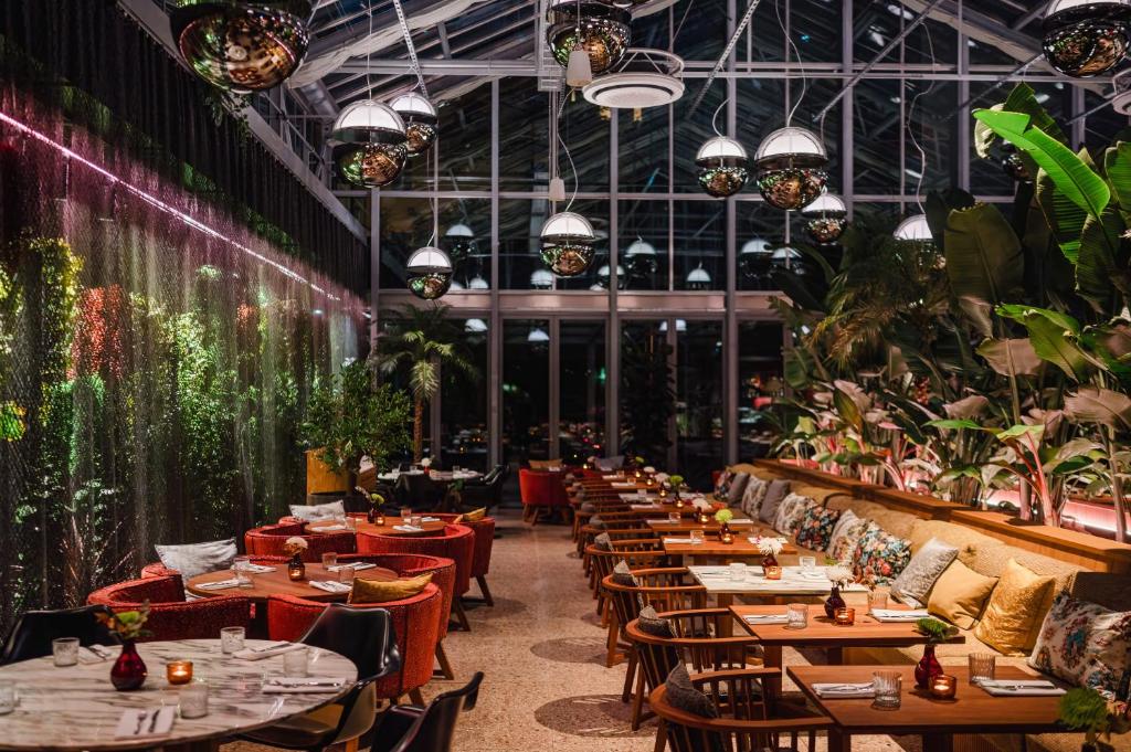 un restaurante con mesas, sillas y plantas en sly Berlin en Berlín