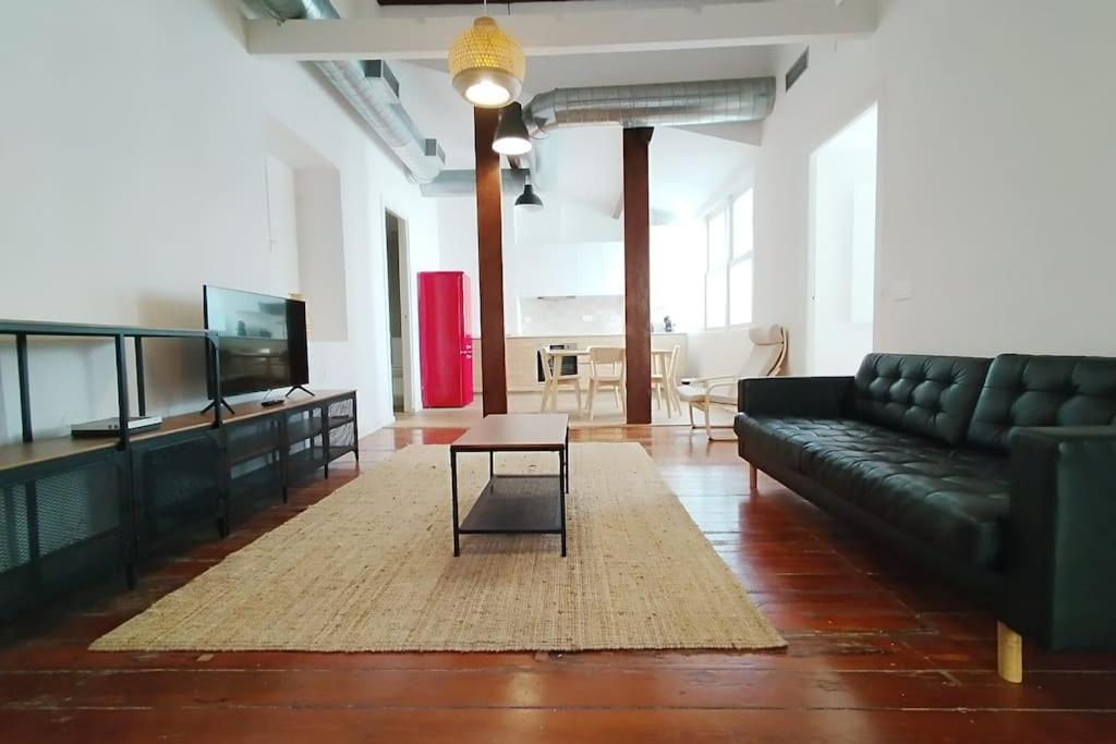 ein Wohnzimmer mit einem schwarzen Sofa und einem Tisch in der Unterkunft VibesCoruña- Picavia 3 in A Coruña