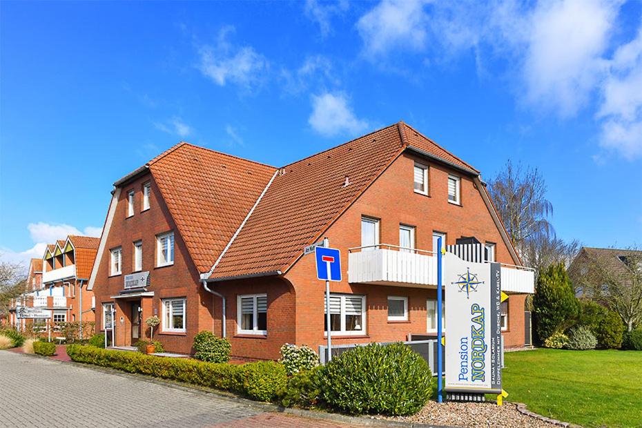 a large brick building with a sign in front of it at Pension Nordkap in Bensersiel