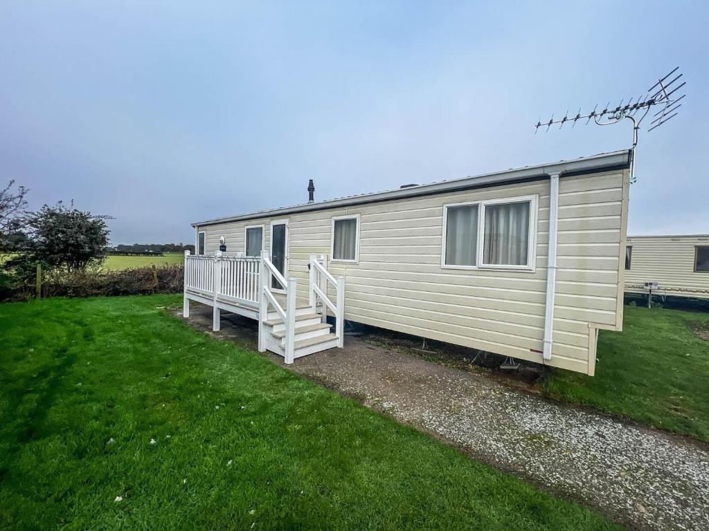 a mobile home with a porch and a yard at Lovely 6 Berth Caravan In Seaside Village Of Scratby, Norfolk Ref 19124s in Scratby