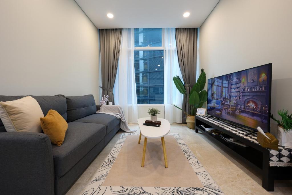 uma sala de estar com um sofá e uma televisão grande em Sky Suites KLCC By Calm Sojourn em Kuala Lumpur