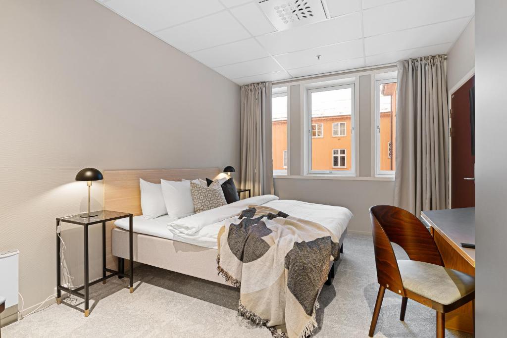 a bedroom with a bed and a desk and a window at Enter St Elisabeth Hotel & Spa in Tromsø