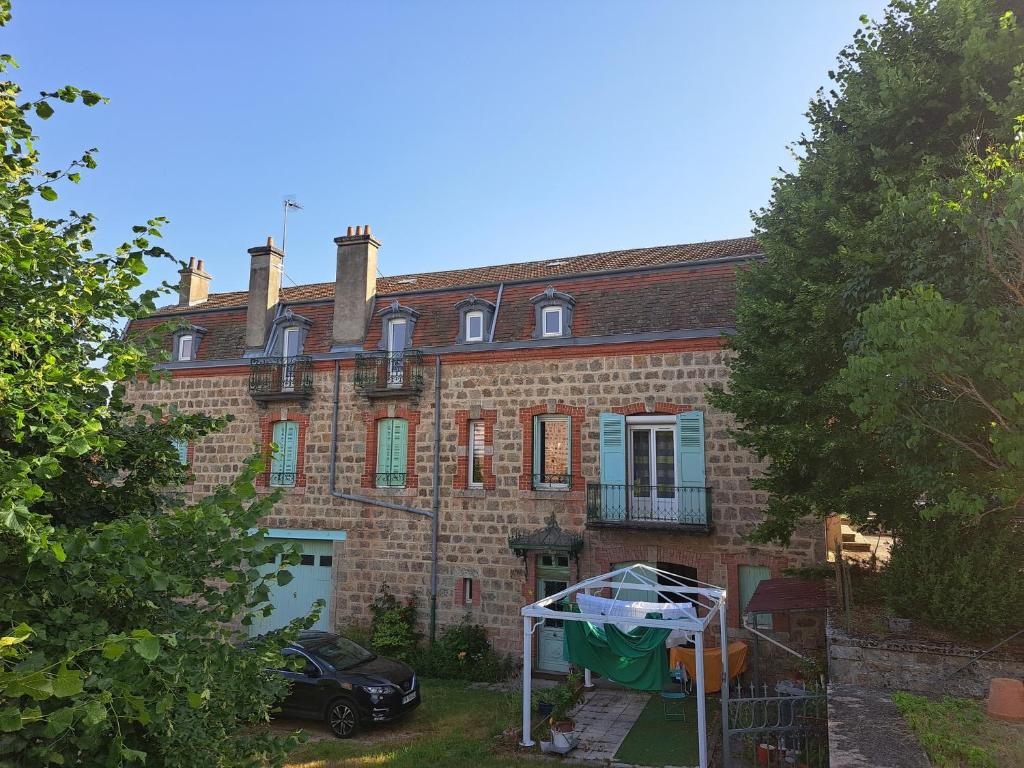an old brick house with a grill in front of it at Chez Patrice et Marieline in Usson-en-Forez