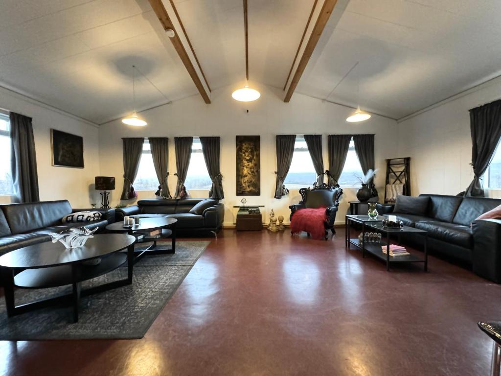 una sala de estar con sofás, mesas y ventanas en Langahlíð Guesthouse - Privatete Forest -, en Hella