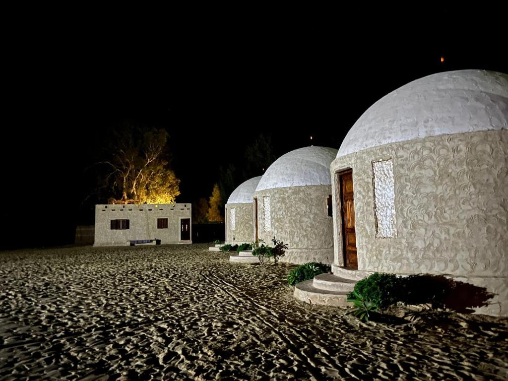 a couple of domed buildings in a field at night at Stamps Siwa Oasis in Siwa