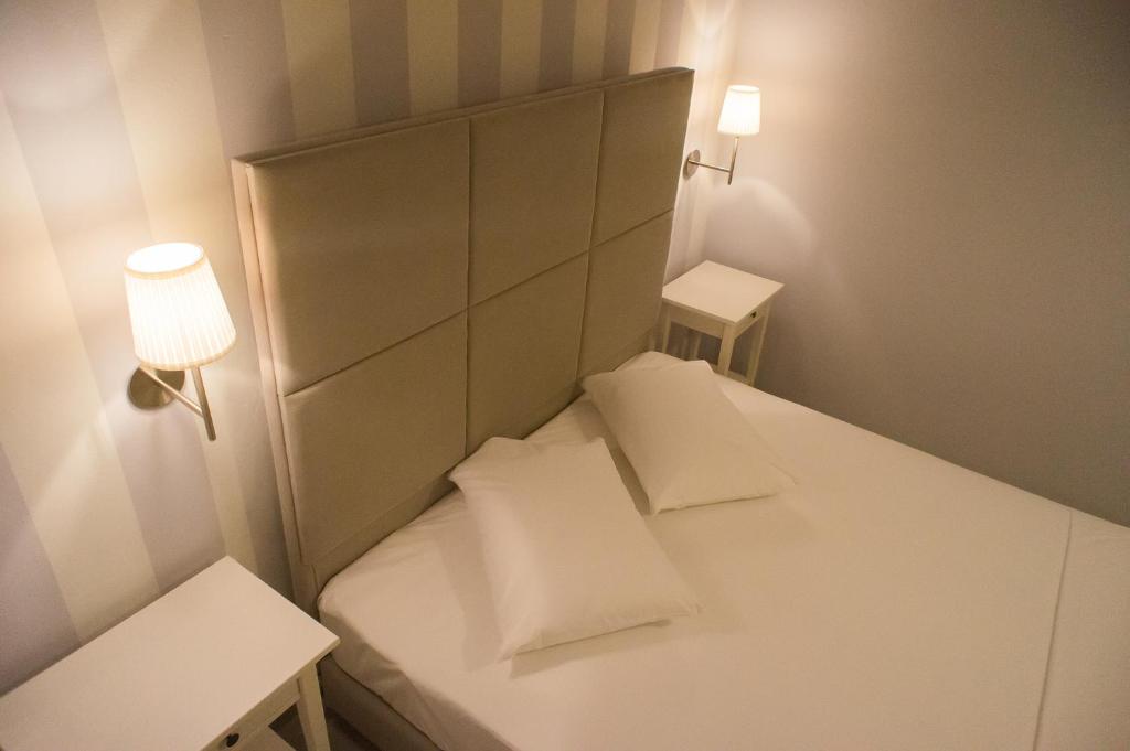 Una pequeña cama blanca con dos almohadas. en Bello Horizonte en Gythio