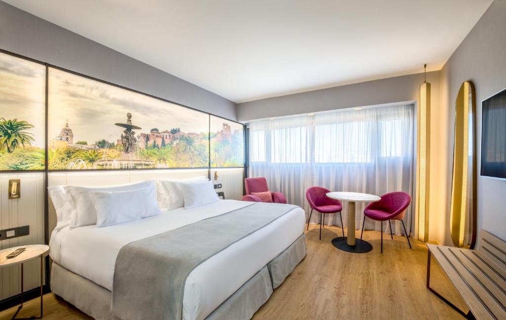 マラガにあるバルセロ マラガのベッド、テーブル、椅子が備わるホテルルームです。