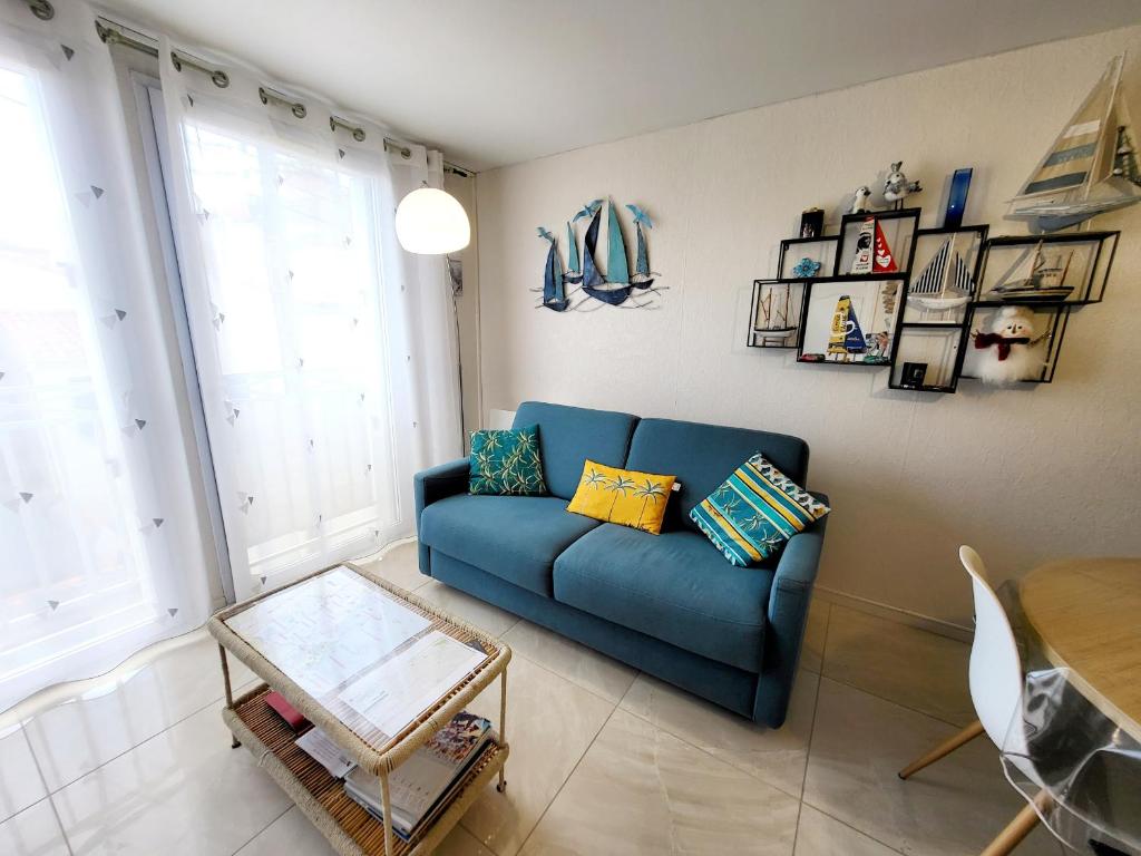 un salon avec un canapé bleu et une table dans l'établissement Appartement Moderne au Centre-Ville, 150m Plage, WiFi, Confort Idéal pour Familles - FR-1-92-876, à Les Sables-dʼOlonne