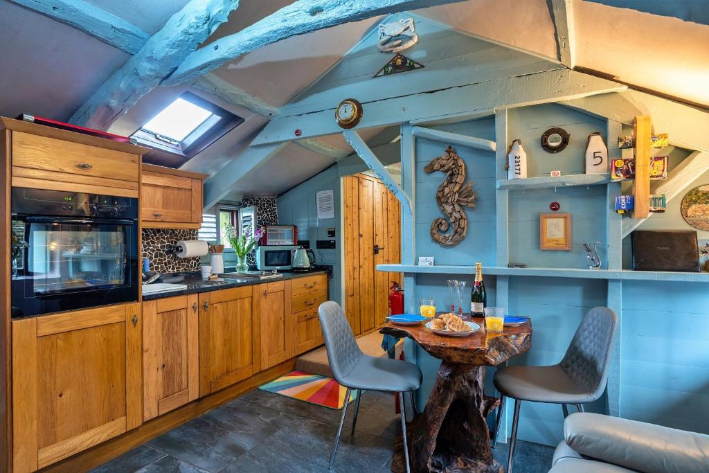 una cocina con armarios de madera, mesa y sillas en Finest Retreats - Fishermans Cottage, en Tintagel