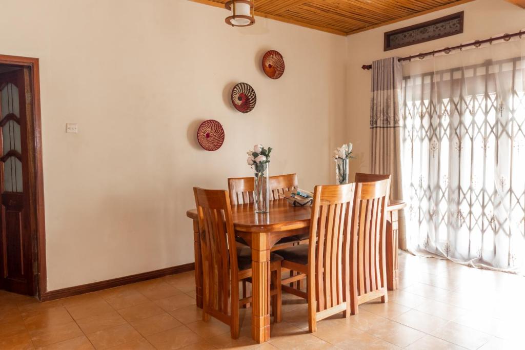 a dining room with a wooden table and chairs at Nilescape Residence in Jinja
