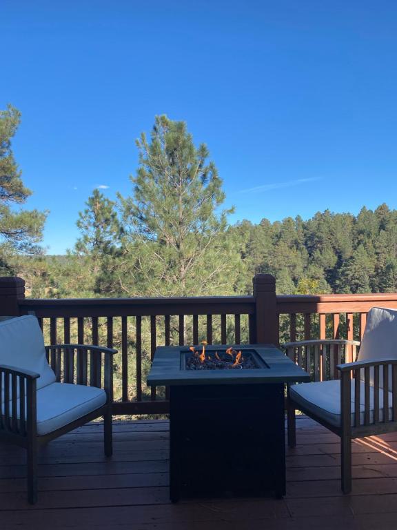 a fire pit on a deck with two chairs and a table at Ski+Golf+Fishing Flagstaff Kachina Cabin! in Mountainaire