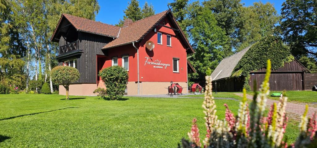 uma casa vermelha com um telhado preto num quintal em Ferienwohnungen im Landhaus em Burg
