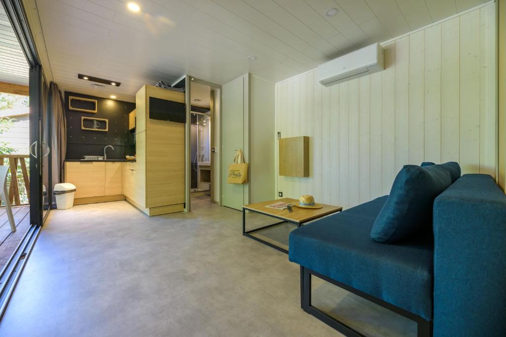 a living room with a blue couch and a kitchen at Camping U Pirellu in Porto-Vecchio