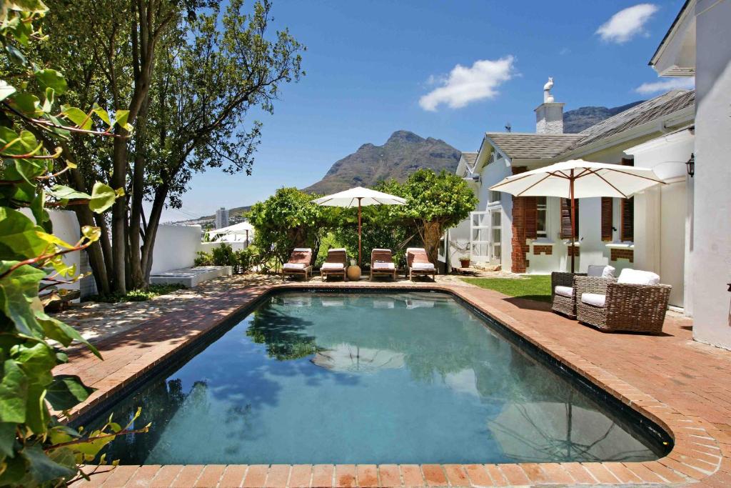 a swimming pool with chairs and umbrellas in a yard at InAweStays Holiday Homes in Cape Town