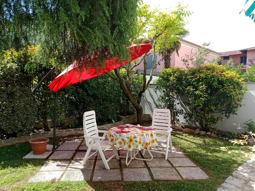 Una mesa y dos sillas con una sombrilla roja. en il Cantuccio, en Desenzano del Garda
