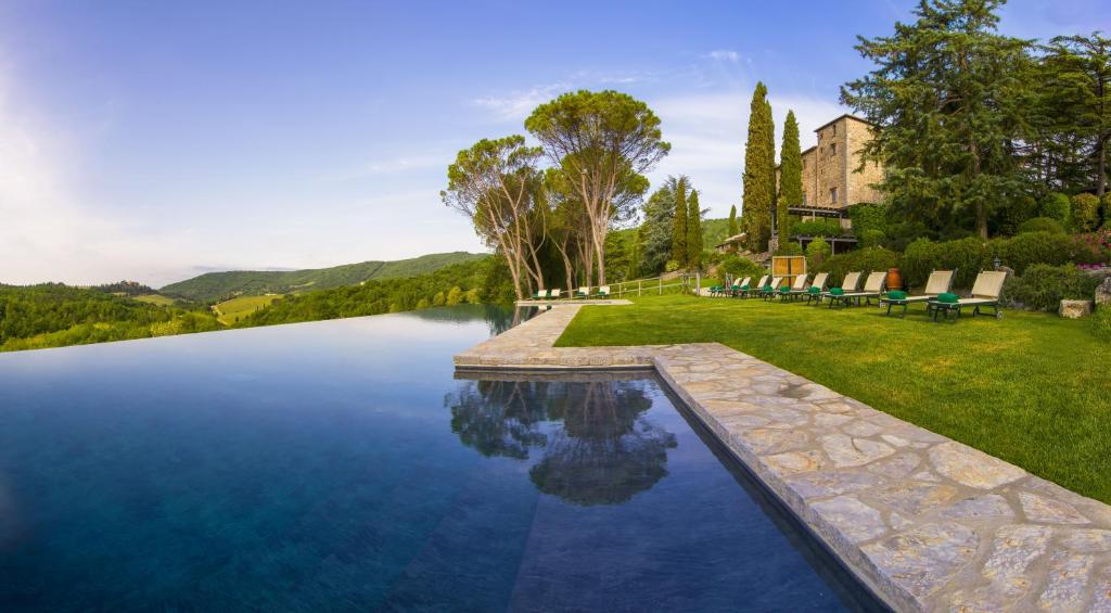 een zwembad in het midden van een gazon met stoelen eromheen bij Castello di Spaltenna Exclusive Resort & Spa in Gaiole in Chianti