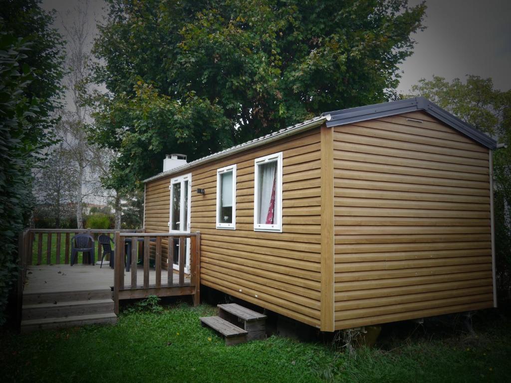 uma pequena cabana de madeira com um alpendre na relva em Camping de Charlieu em Charlieu