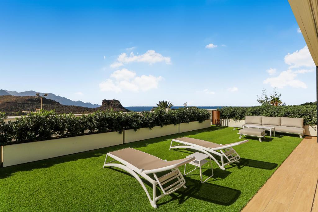 阿蓋特的住宿－Agaete 3BR Tropical Views，草地上带椅子和躺椅的庭院
