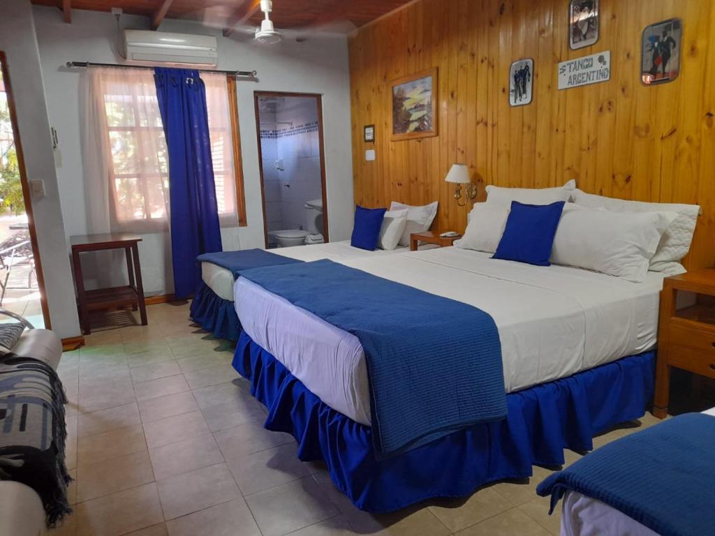 Posada Portal del Iguazu في بويرتو إجوازو: غرفة نوم بسريرين ذات شراشف زرقاء وبيضاء