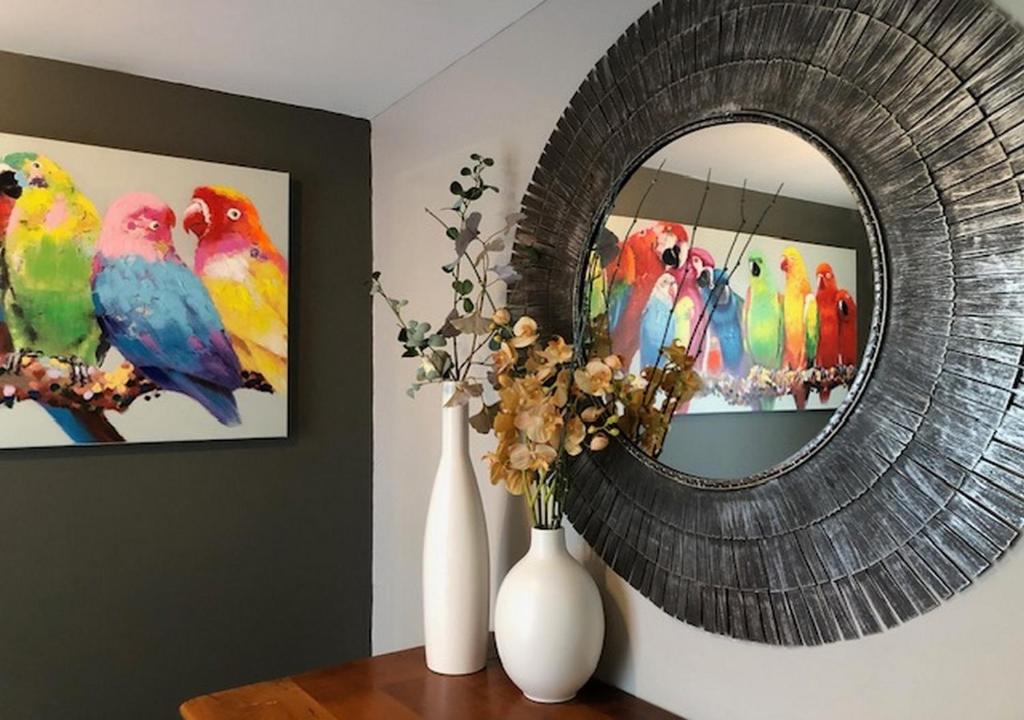 a mirror on a wall with a bunch of parrots at Les cottages du golf in Le Tronchet