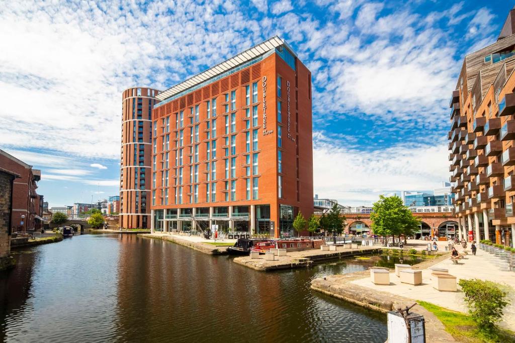 a red building next to a river with buildings at DoubleTree by Hilton Leeds in Leeds