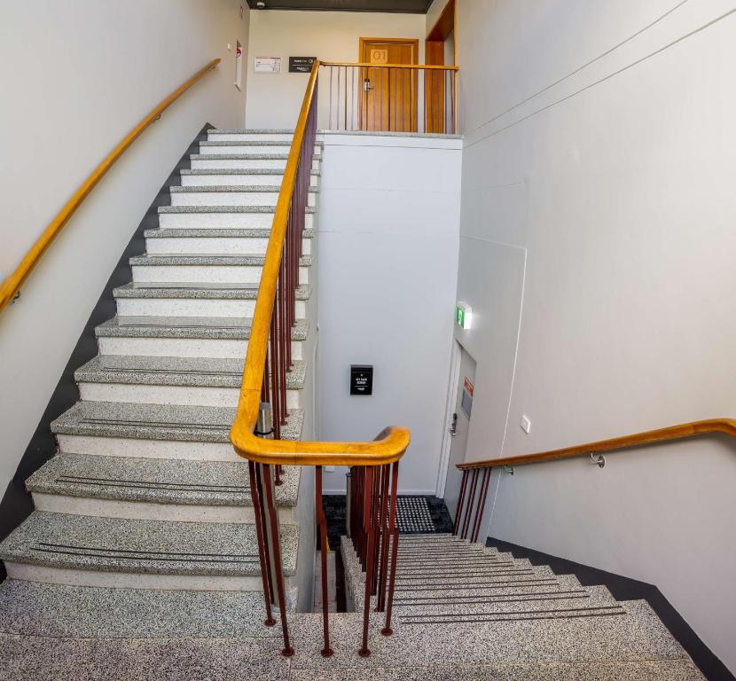 a staircase in a building with a yellow rail at Nightcap at Empire Hotel in Gepps Cross