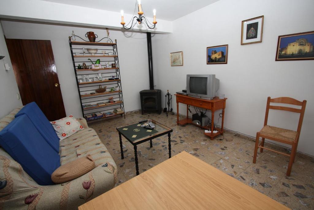 sala de estar con sofá, mesa y TV en Casa Rural El Nido, en Solana de Ávila