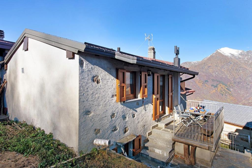 a stone house with a table and a chair on the porch at Baita Margherita in Casargo