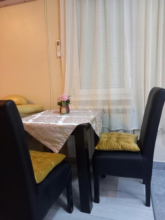 een tafel met twee stoelen en een vaas met bloemen erop bij 2Anna Apartments in Surčin